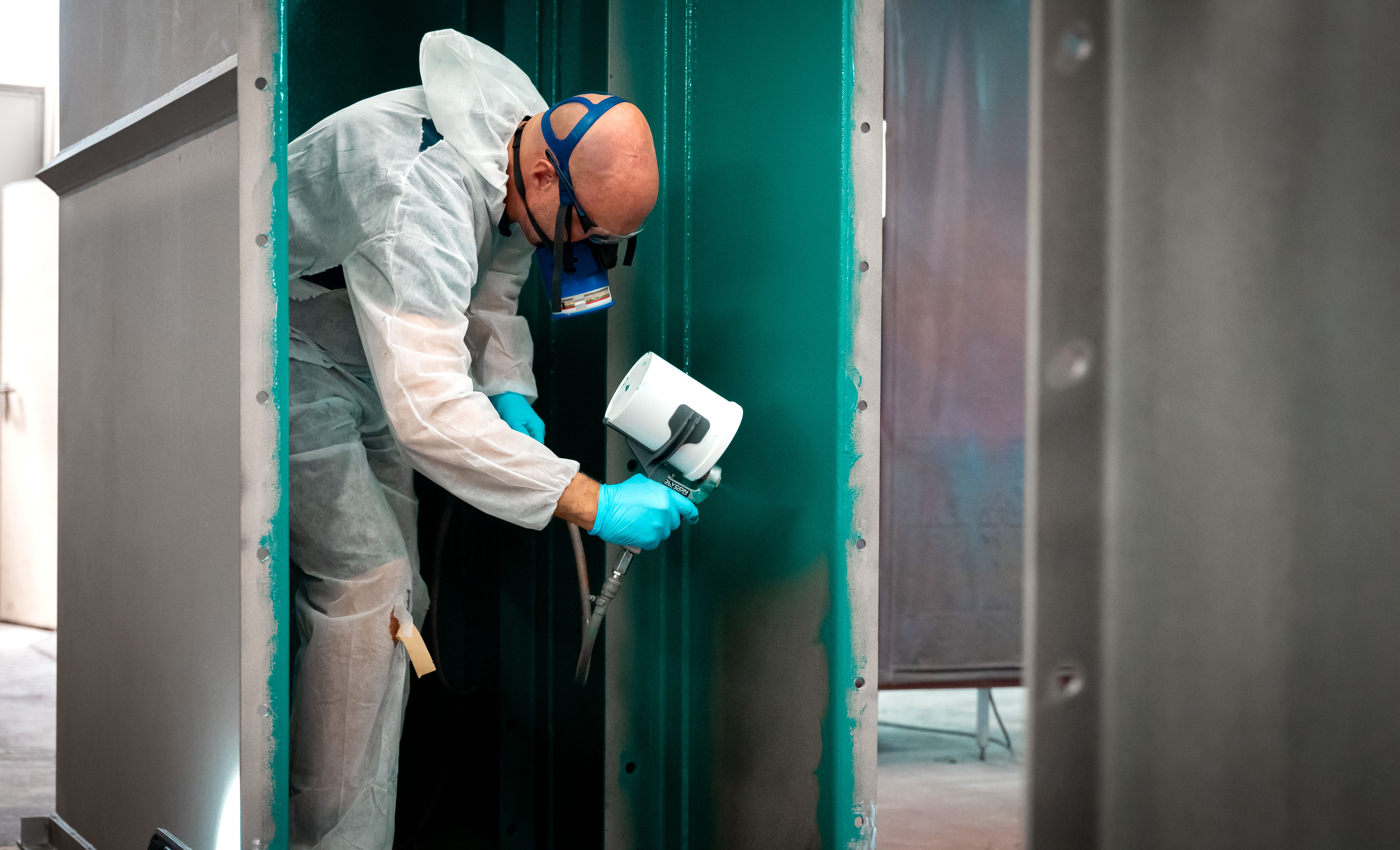 Een man met een masker spuit een groene controlelaag op