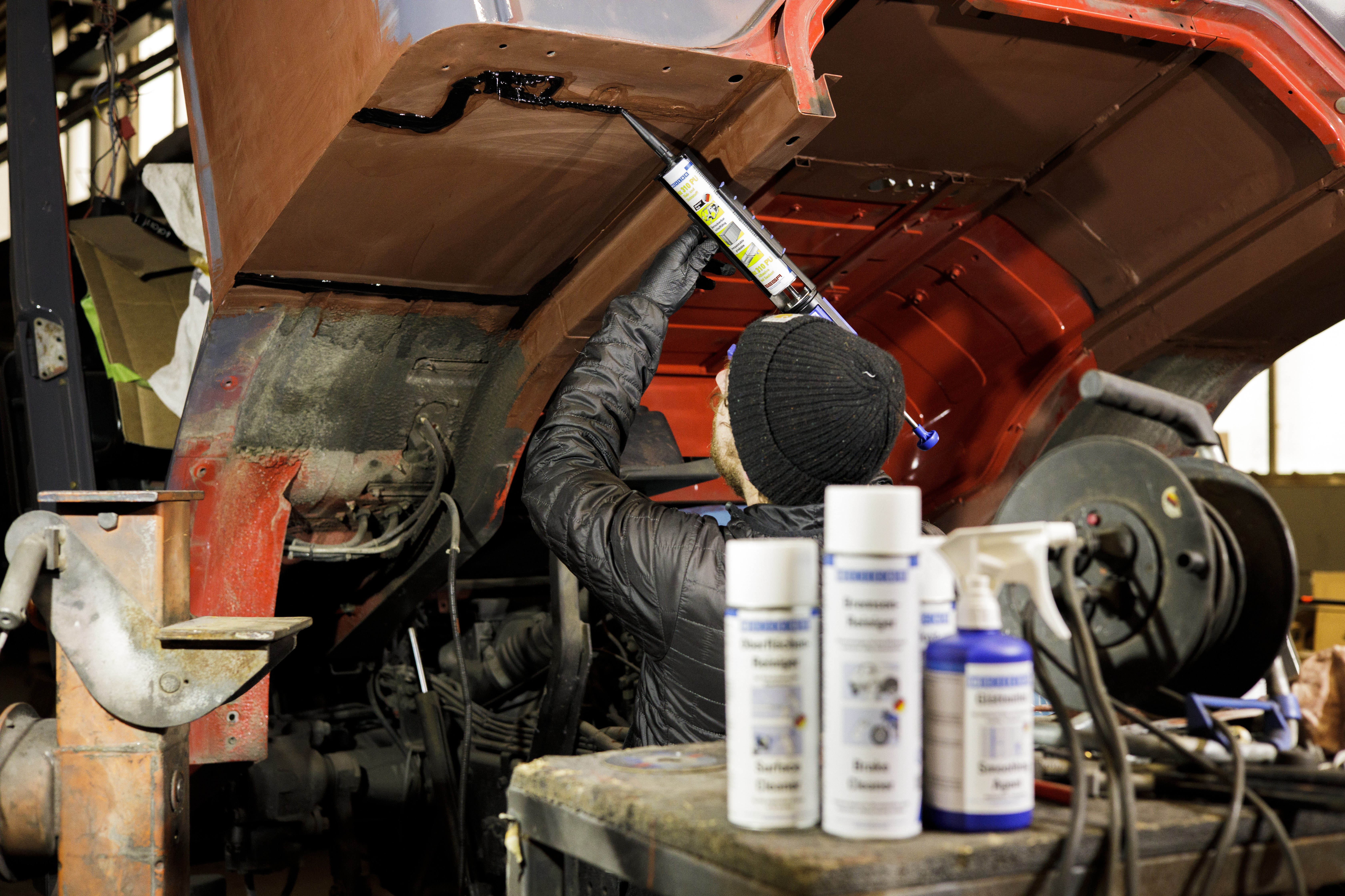 A man applicates an elastic sealant on an oldtimer
